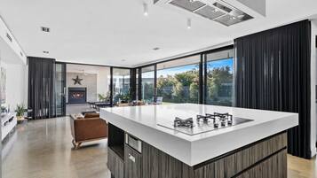 A modern kitchen with a large island, a fireplace, and a view of the outdoors.