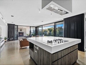 A modern kitchen with a large island, a fireplace, and a view of the outdoors.