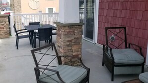 An outdoor patio area with wicker furniture, a stone pillar, and a red building in the background. - PRICE REDUCED Beautiful 3 Bedroom, 21/2 Bath Condo,walking distance to the beach (North Wildwood)