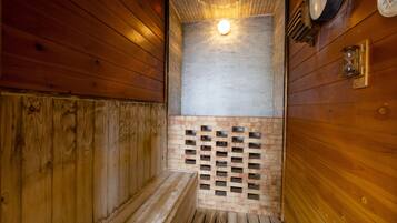 Una sauna de madera con un banco, una pared de ladrillo y una lámpara.