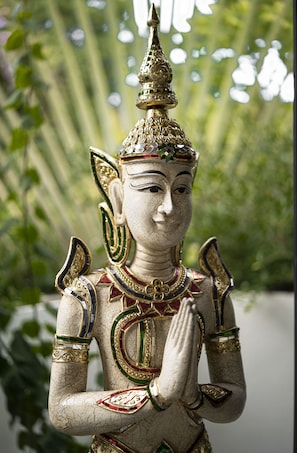 A statue with intricate designs and a pointed top, set against a blurred green background.