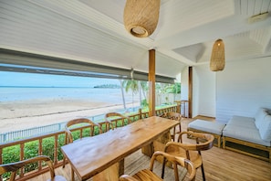 Una terraza de madera con mesa y sillas con vista a una playa.