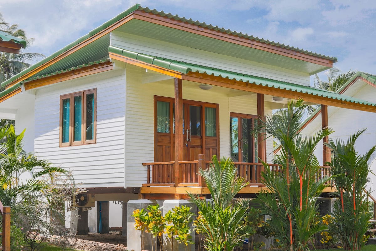 A two-story house with a balcony, wooden doors, and a green roof.