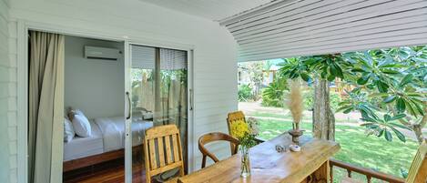 A room with a wooden table, chairs, a sofa, and a sliding glass door leading to a garden.