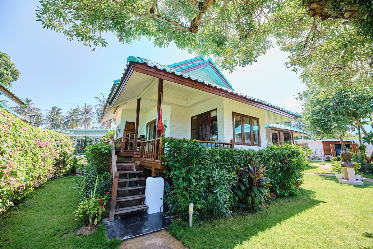 A two-story house with a porch, a staircase, and a garden.