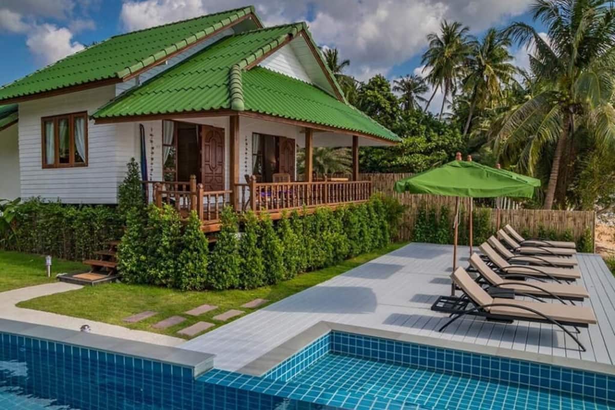 A house with a swimming pool, a covered porch, and lounge chairs.