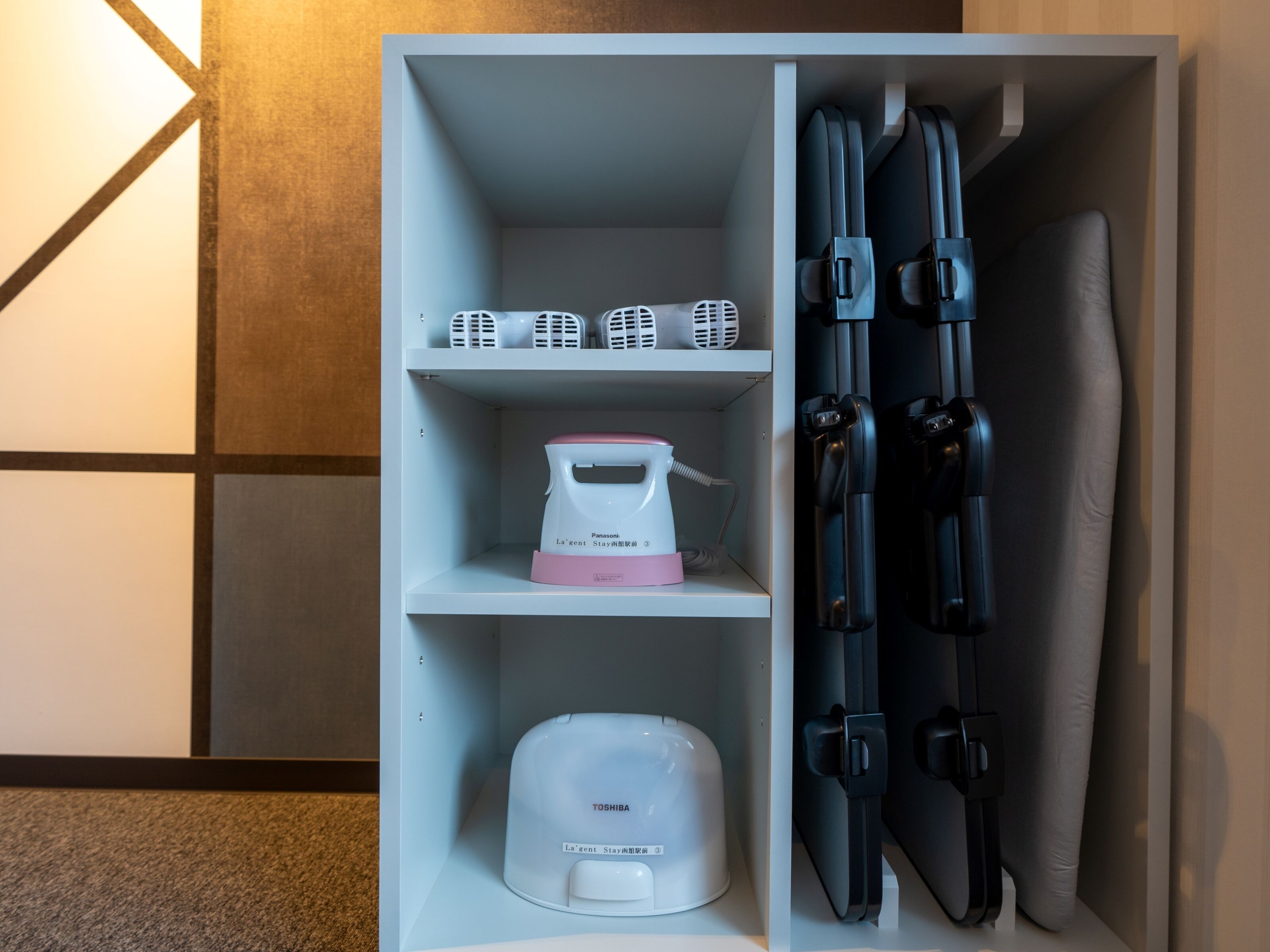 A storage unit with a white and pink appliance, a white device, and black handles.