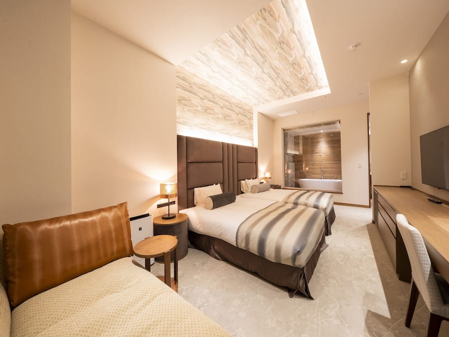 Una habitación de hotel moderna con una cama grande, un escritorio y un baño con cabina de ducha de vidrio.