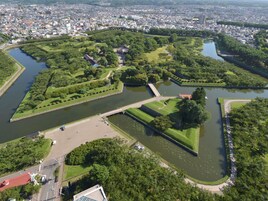Vista aérea de un parque con un lago, senderos y un puente.