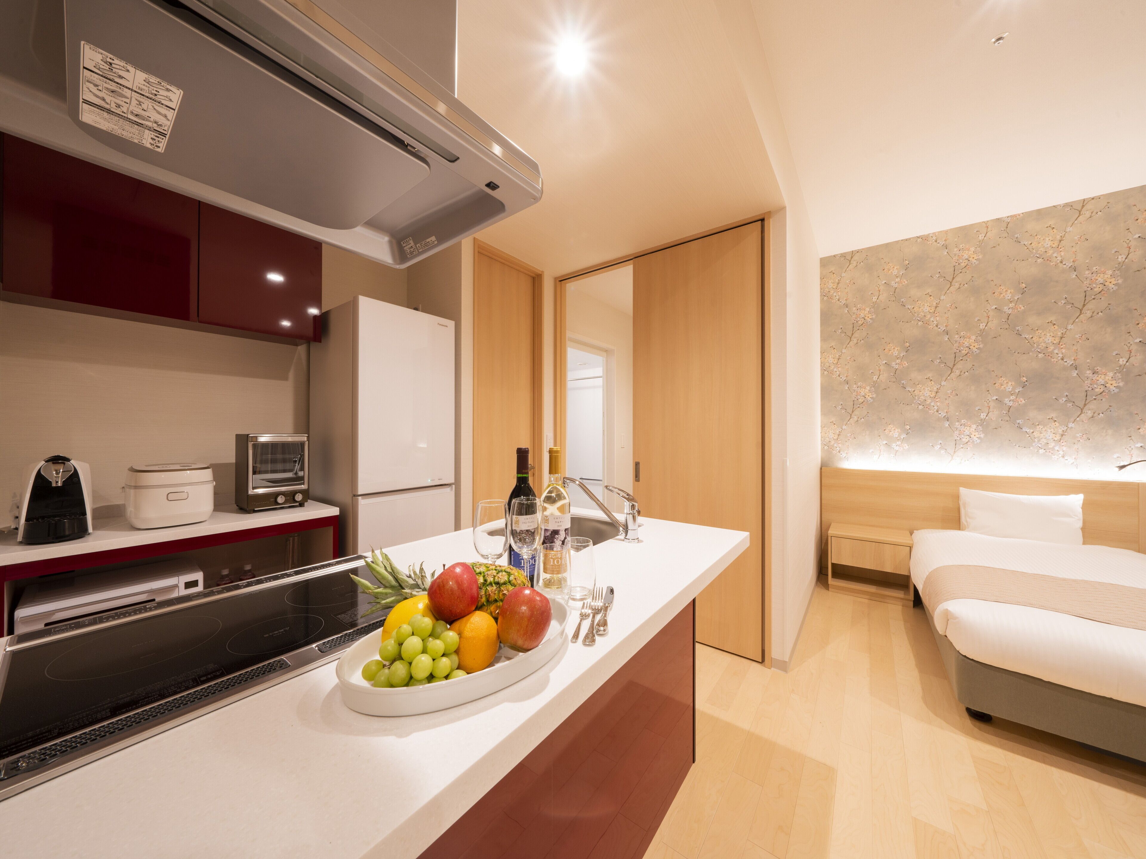 Una habitación de hotel moderna con kitchenette, una cama y un frutero en la encimera.