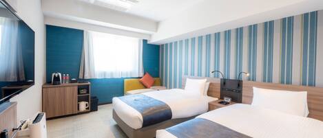 A hotel room with two beds, a desk, a TV, and a window with curtains.