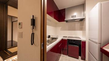 A modern kitchen with red cabinets, a built-in oven, and a refrigerator.
