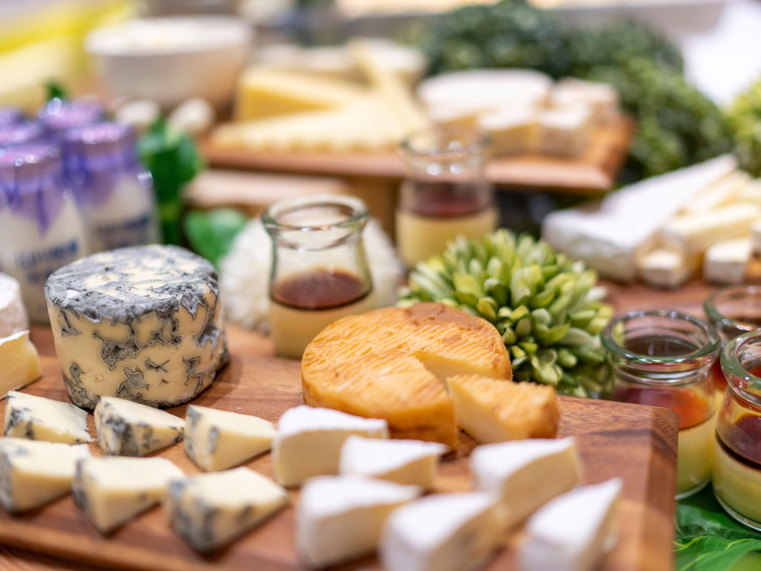 A variety of cheeses and condiments on a wooden board.