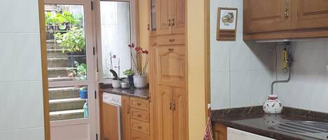 A kitchen with wooden cabinets, a tiled floor, and a window with plants.