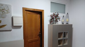 A wooden door, a white wall with a framed picture, and a grey cabinet with shelves. - Holiday apartment, downtown, seasons (Monforte de Lemos)