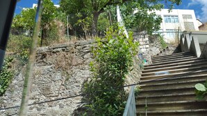 A stone staircase leading up a rocky hill with a metal fence and greenery. - Holiday apartment, downtown, seasons (Monforte de Lemos)