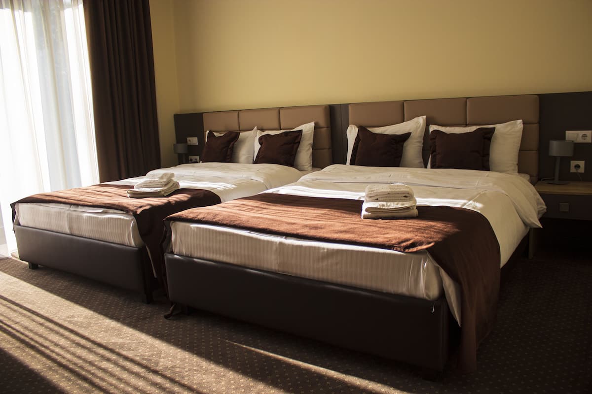 Een hotelkamer met twee bedden, elk met een bruine deken en een opgevouwen handdoek.