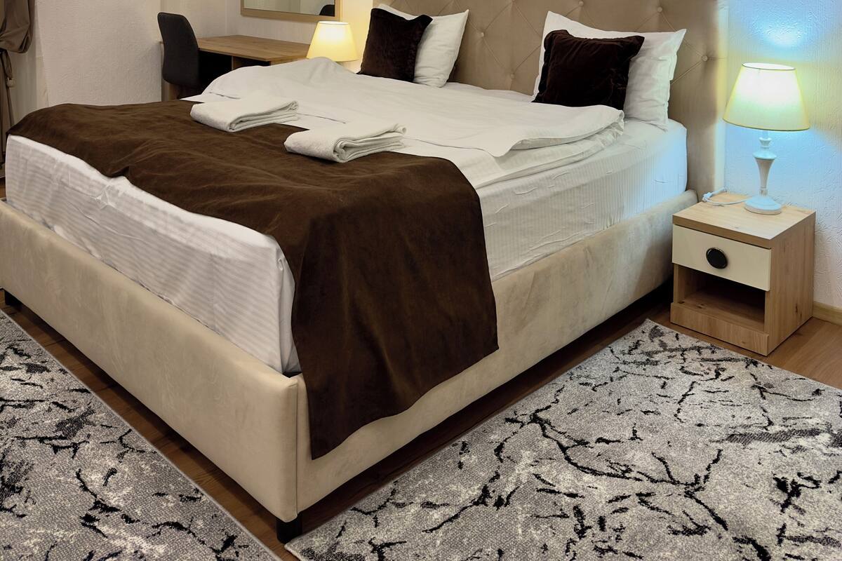 Een hotelkamer met een groot bed, nachtkastjes, een bureau en een spiegel.