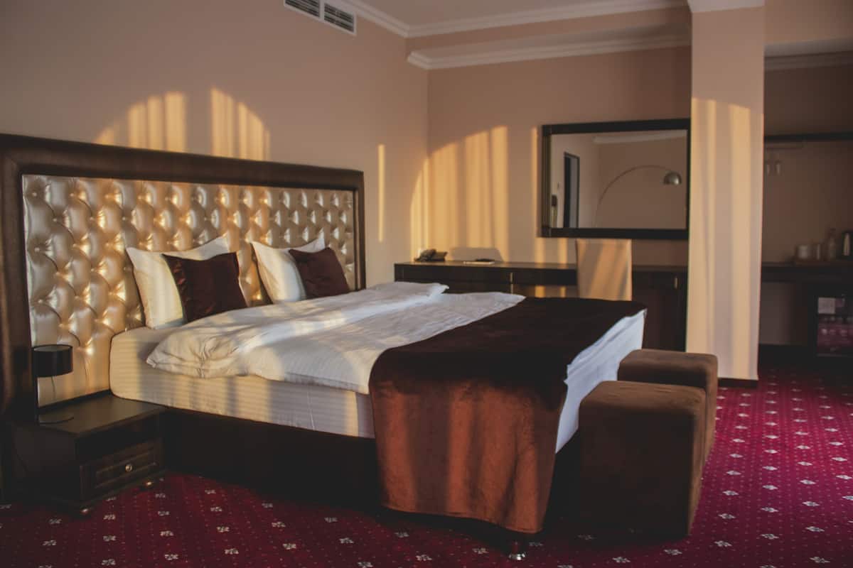 Een hotelkamer met een groot bed, een nachtkastje, een dressoir en een spiegel.