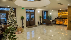 Vestíbulo de hotel con un árbol de Navidad, un mostrador de recepción y un espejo grande en el techo.