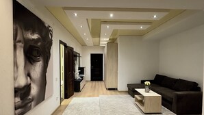 Una sala de estar moderna con un mural grande en la pared, un sofá oscuro, una mesa de centro y piso de madera.