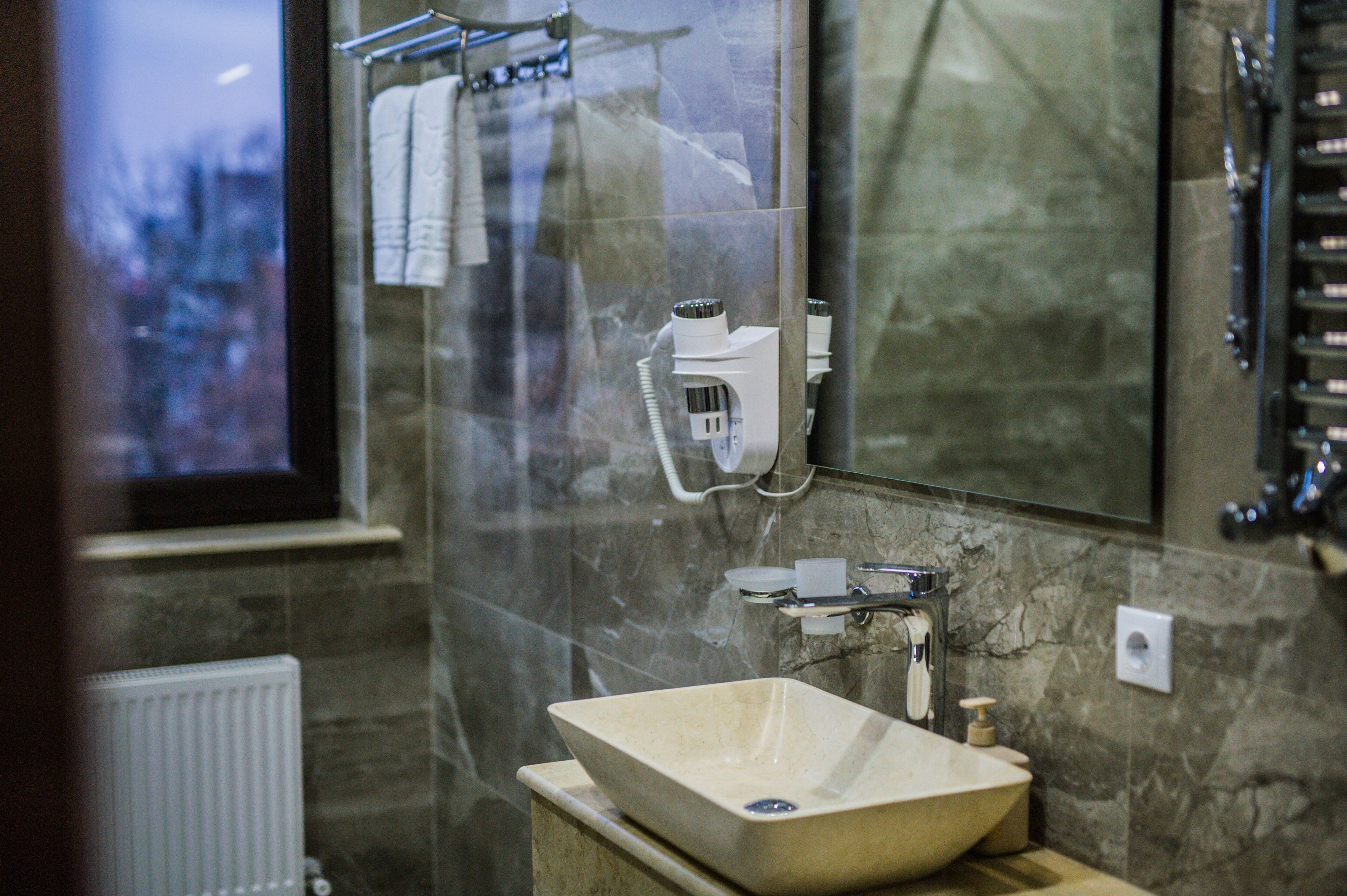 A bathroom with a large mirror, a sink, and a shower area.