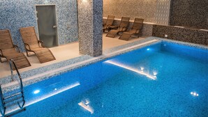 Una piscina con sillones de descanso y un vestuario.