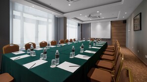 A conference room with a long table, chairs, water bottles, and a projector screen. - M Palace Hotel (Kuala Lumpur)