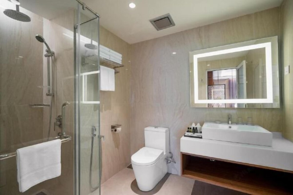 A modern bathroom with a glass-enclosed shower, a white toilet, and a vanity with a large mirror.