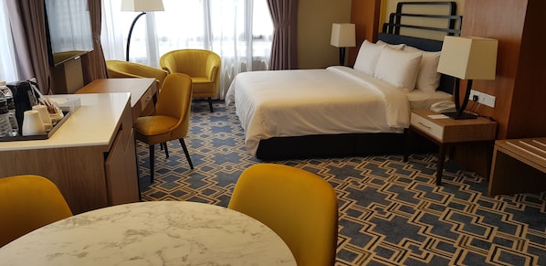 Una habitación de hotel con cama, escritorio, silla, mesa y alfombra estampada.
