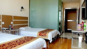 A hotel room with two beds, a desk, a mirror, and a minibar.