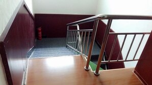 A wooden staircase with a metal handrail, a fire extinguisher, and a patterned carpet.
