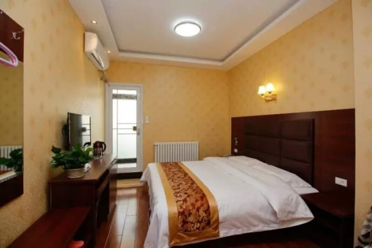 Quarto de hotel com cama, mesa de cabeceira e televisão.