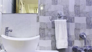 A bathroom with a white sink, a towel hanging on a rack, and a mirror. - Itsy Hotels Elmas Golden Key (Bengaluru)