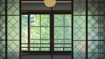 A room with a large window, a round table, and a hanging light fixture.