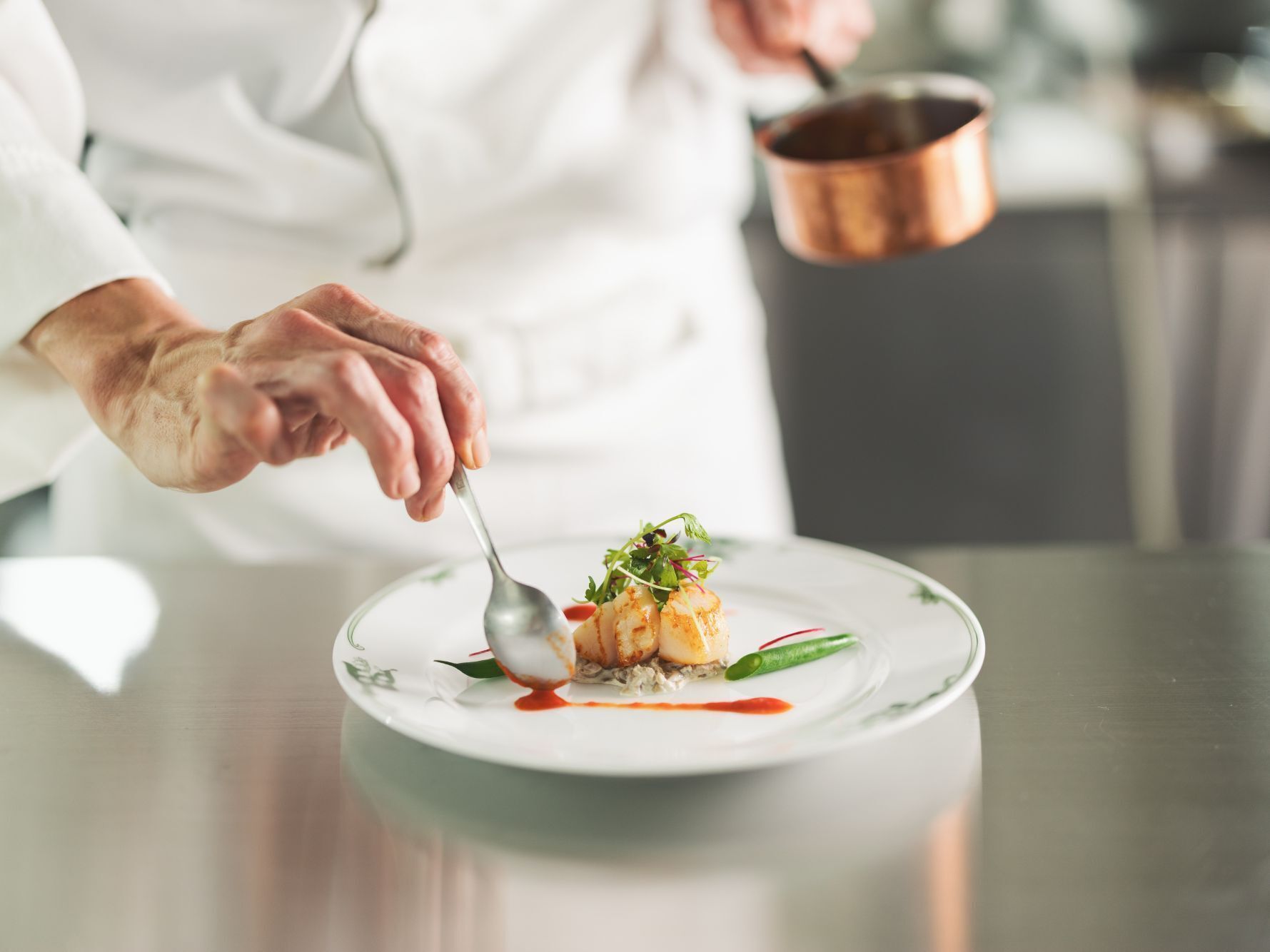 A person serving a dish on a plate with a spoon.