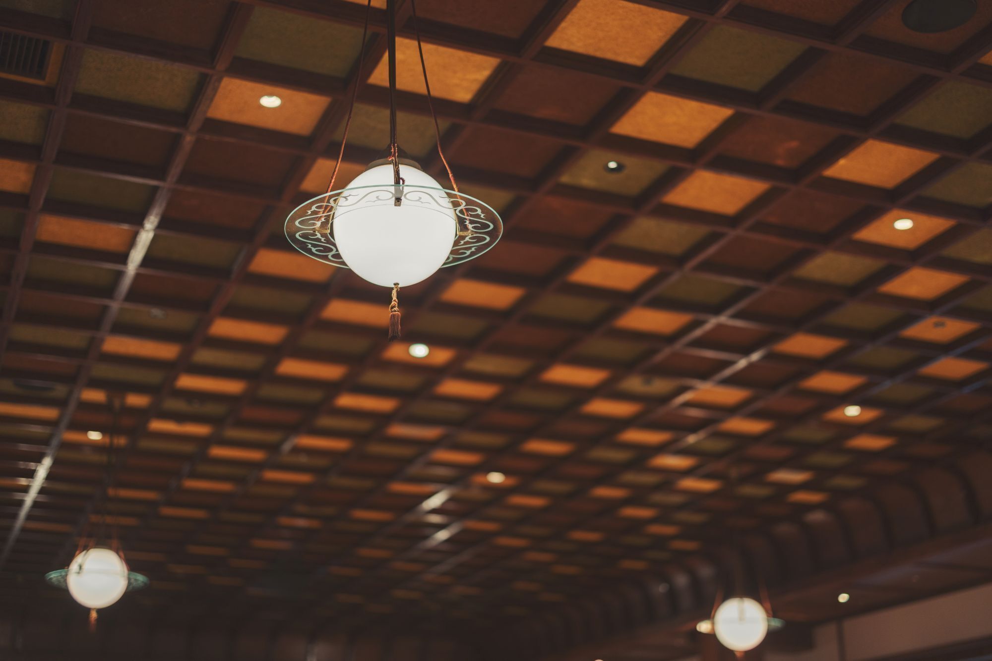 A ceiling with a grid pattern and hanging spherical light fixtures.