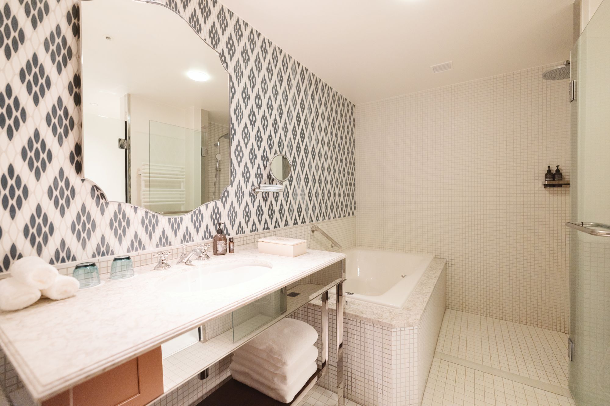 A bathroom with a large mirror, a bathtub, and a shower area.