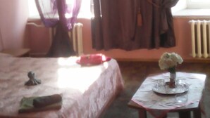 A hotel room with a bed, a table with a vase of flowers, and a window with curtains. - Hotel  Flat 5678 (Odesa)