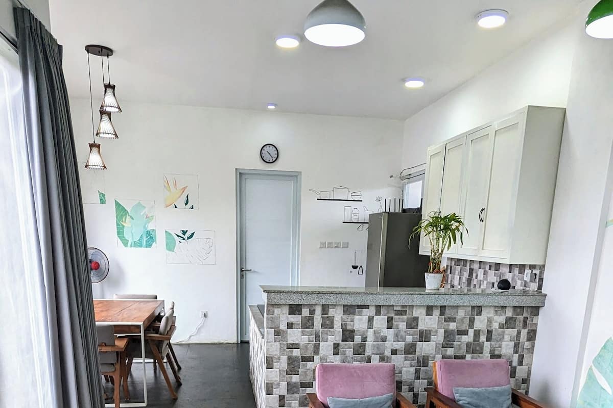 A modern kitchen with a tiled backsplash, wooden cabinets, and a dining area with cushioned chairs.
