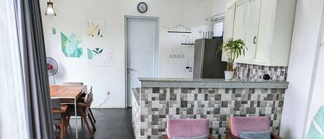 Een moderne keuken met een betegelde spatwand, houten kastjes en een eethoek met comfortabele stoelen.