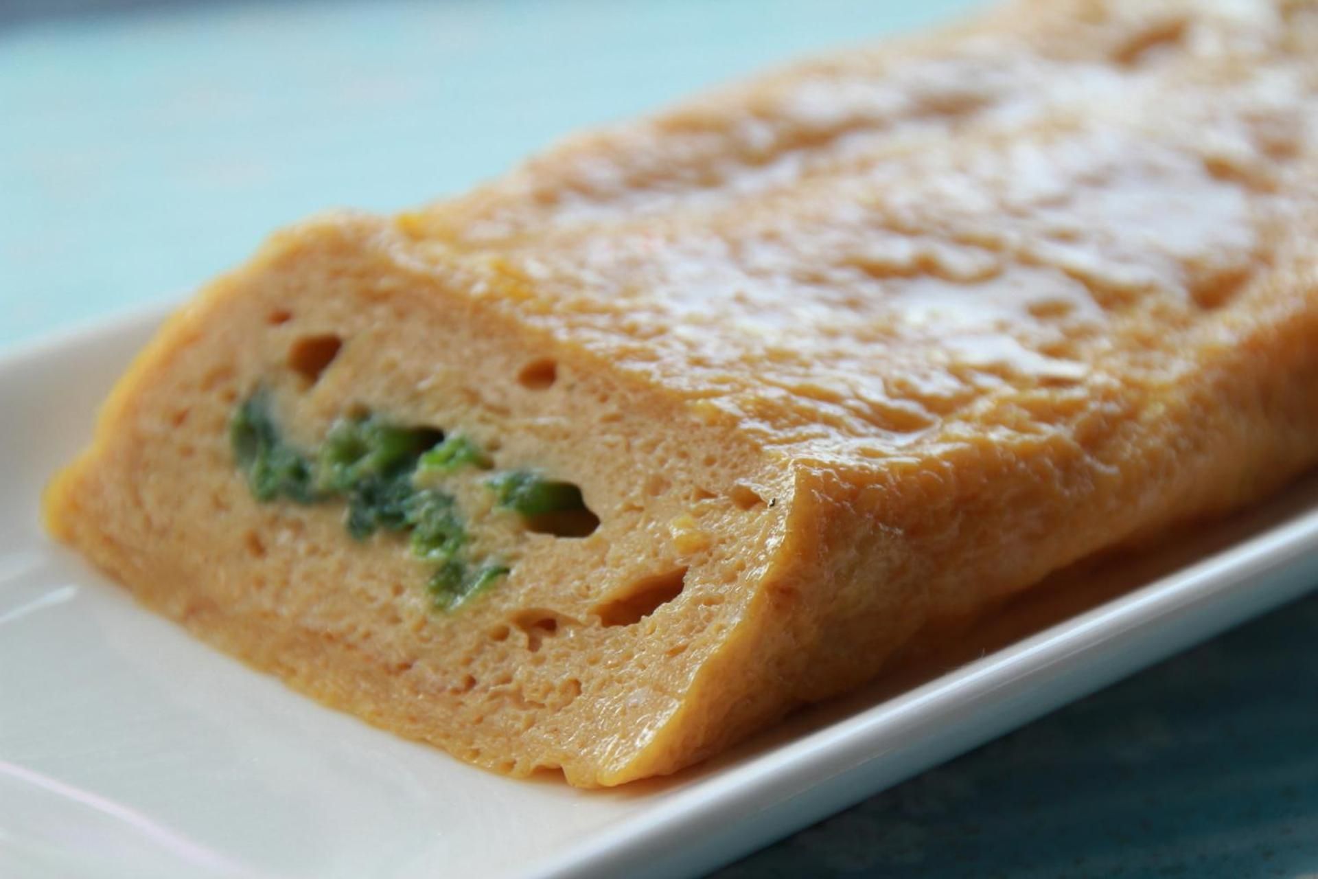 Une miche de pain parsemée de petites taches vertes, posée sur une assiette blanche.
