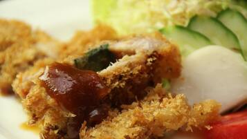 A close-up of a fried dish with a crispy coating, possibly chicken, accompanied by a side of fresh vegetables and a white spherical item, likely a boiled egg.