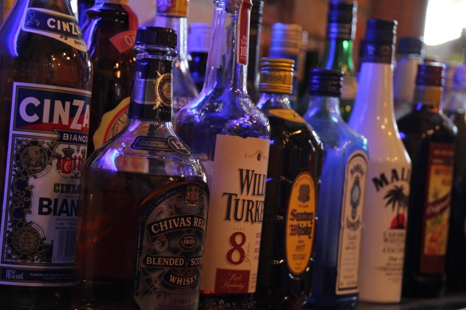 A variety of liquor bottles on a shelf.