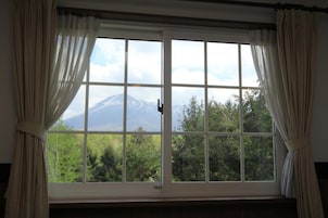Una ventana con vistas a una montaña y árboles.