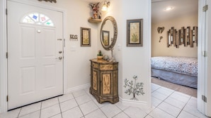 A hallway with a white door, a vintage cabinet, and a bed with patterned bedding in the adjacent room. - 5 STAR LAS VEGAS PLACE (Las Vegas)