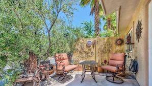 An outdoor patio with two cushioned chairs, a small table, and a decorative wall with various items. - 5 STAR LAS VEGAS PLACE (Las Vegas)