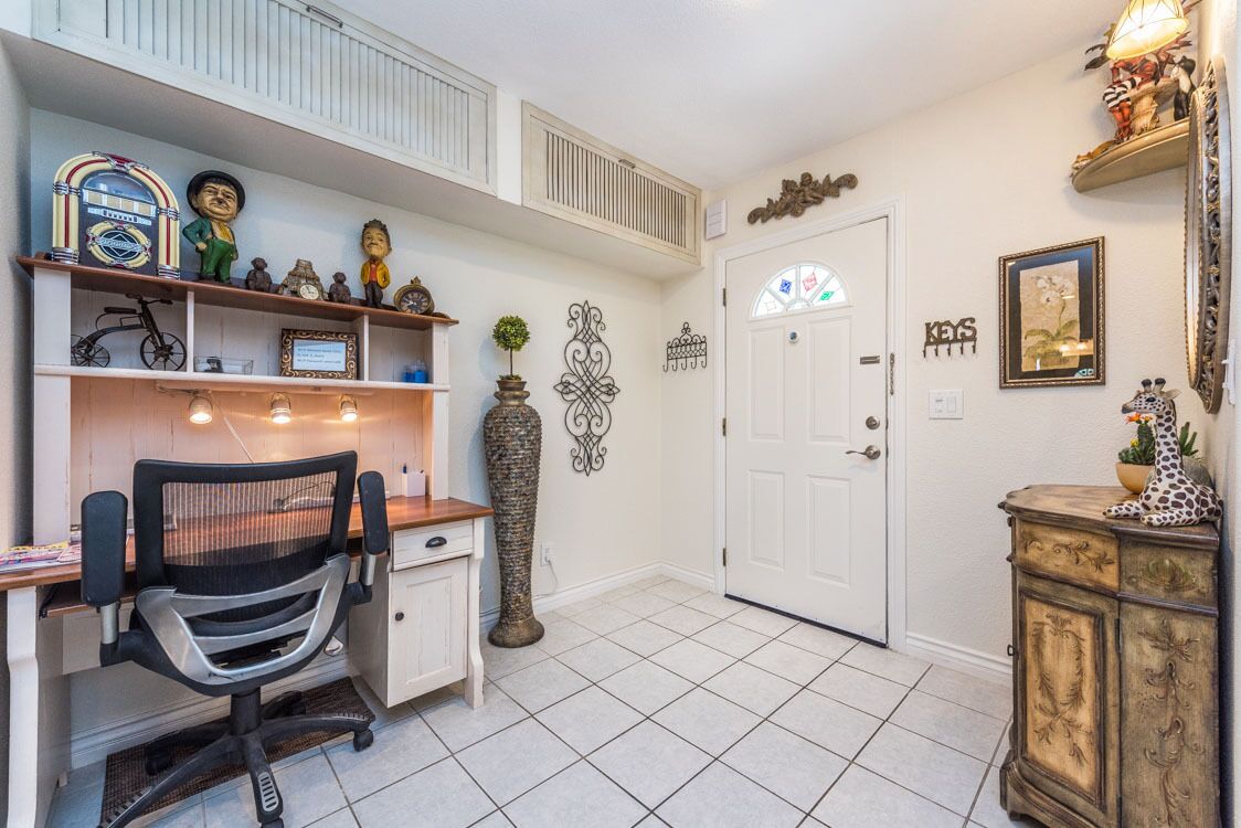 A home office with a desk, chair, and shelves with decorative items.
