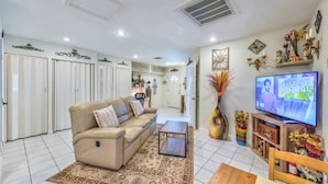 A living room with a beige sofa, a coffee table, a TV, and a dining area with a wooden table and chairs. - 5 STAR LAS VEGAS PLACE (Las Vegas)