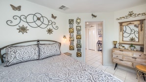 A bedroom with a patterned bedspread, a dresser with a mirror, and decorative wall art including butterflies and flowers. - 5 STAR LAS VEGAS PLACE (Las Vegas)